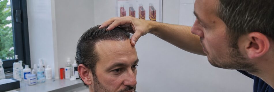 consultation en clinique capillaire avec un spécialiste examinant la ligne frontale et les cheveux colorés d’un patient après une greffe de cheveux, affiches médicales et produits de soin en arrière-plan, 21 juillet 2026, format 16:9