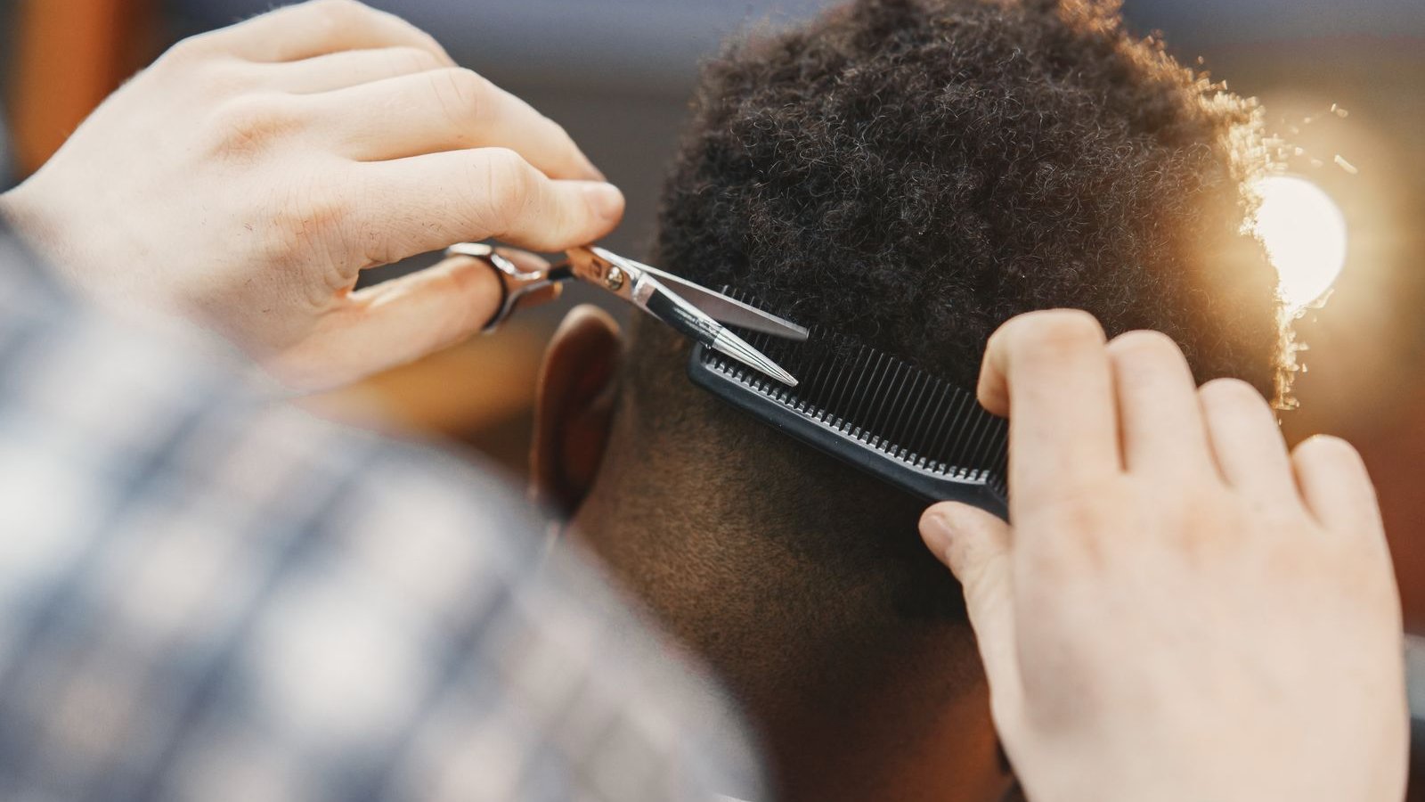 Coiffeur coupant aux ciseaux les cheveux crépus d'un homme