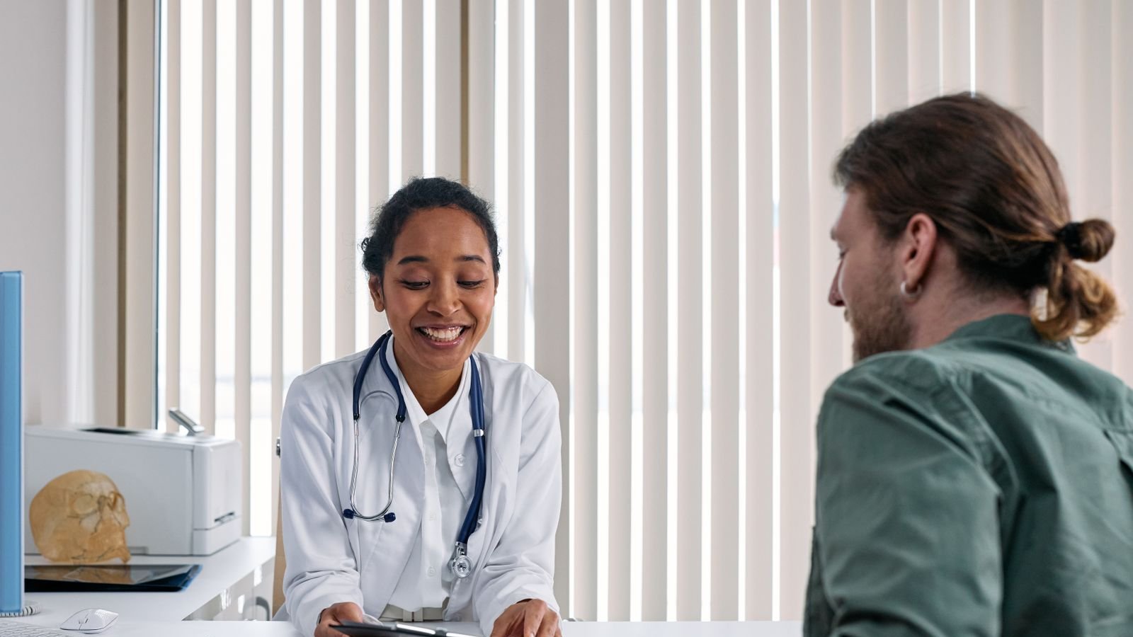 Médecin souriante échangeant avec un patient lors d'une consultation